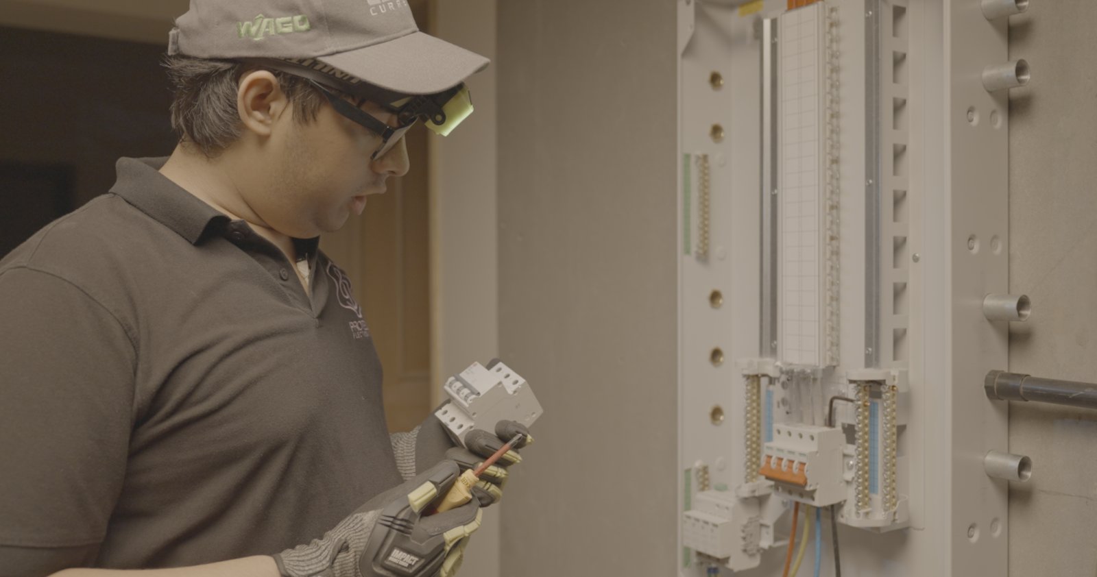 A ProtegoPlus engineer inspecting a circuit breaker beside a distribution board